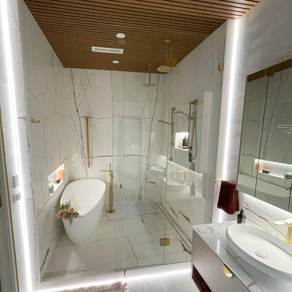 Luxury marble ensuite with an LED-backlit mirror and feature strip lighting